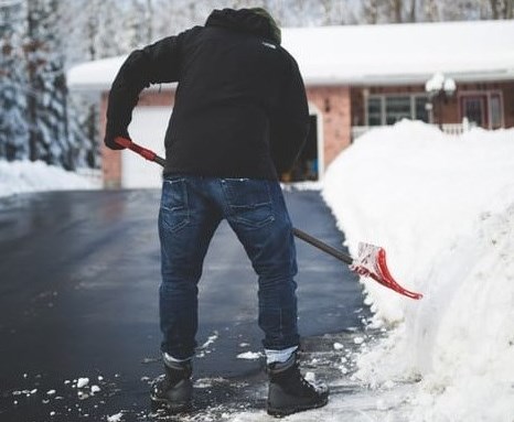 man shoveling snow to clear his driveway