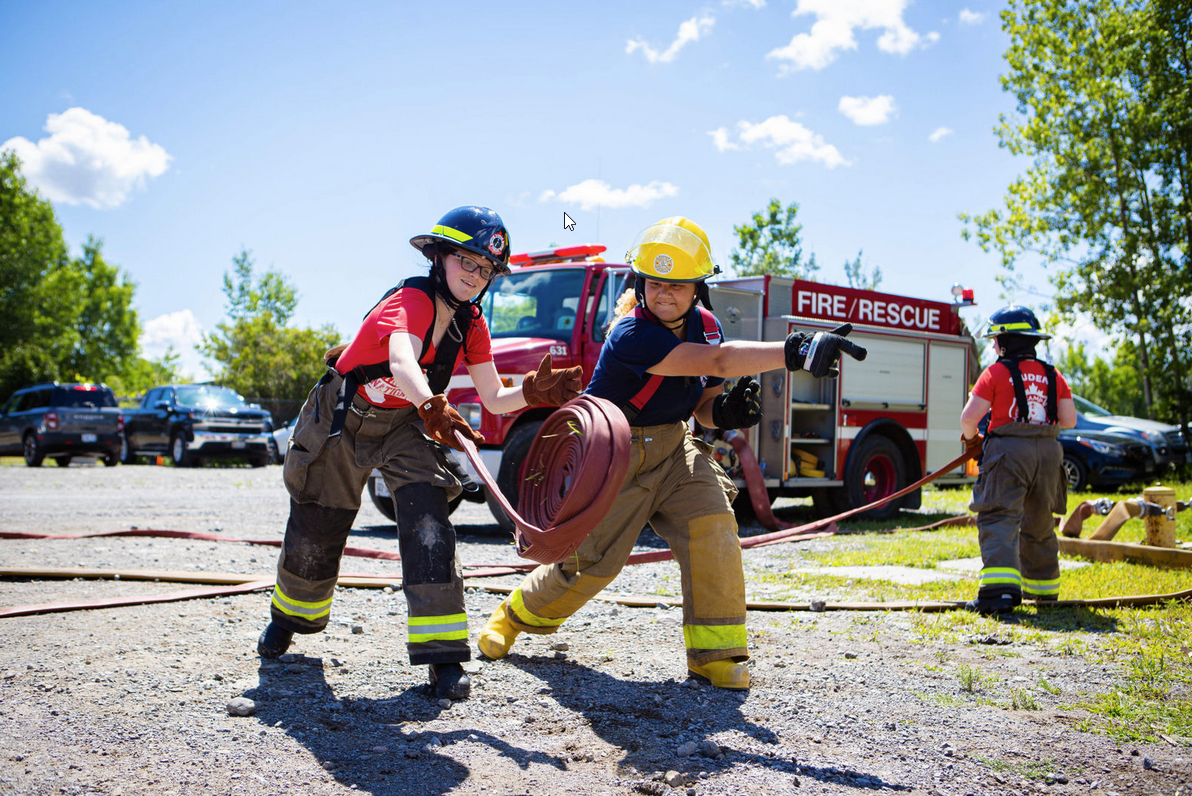 Two girls unrolling fire hose in a Camp Molly Challenge