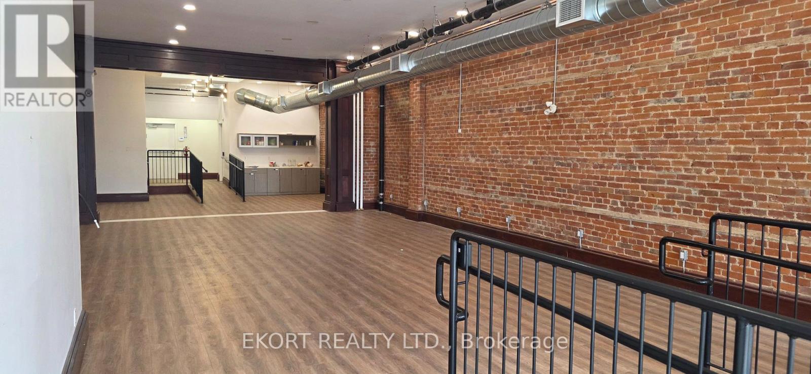 Empty room with exposed brick walls and kitchenette