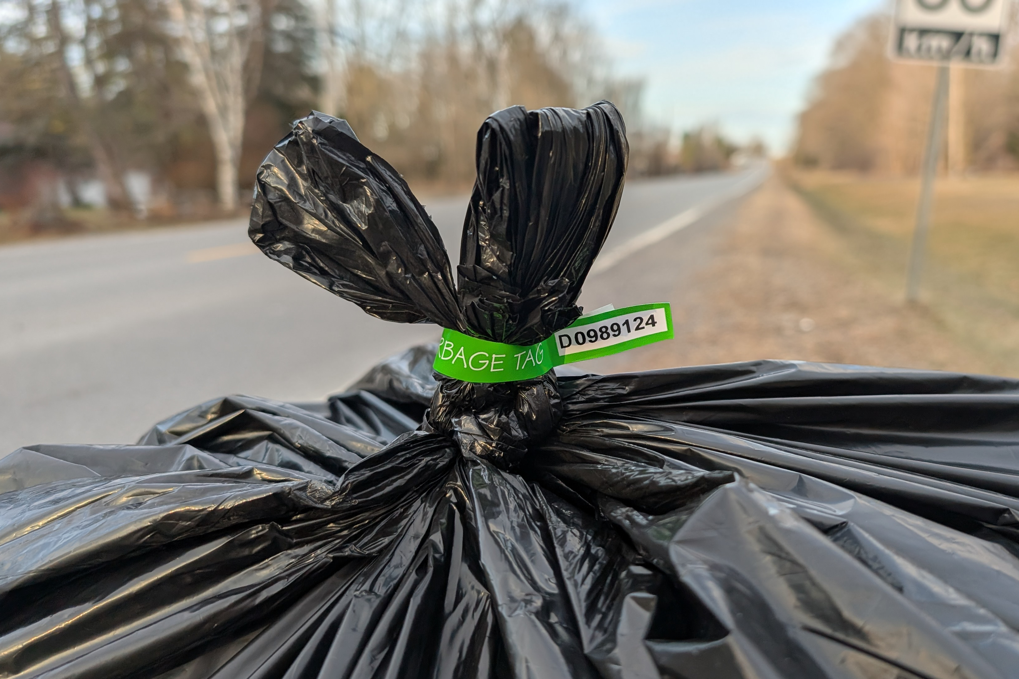 A photo of a properly tagged bag of garbage at the road, ready for collection.