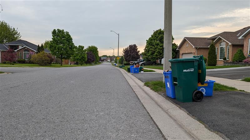 Recycling and green bin on the side of the road