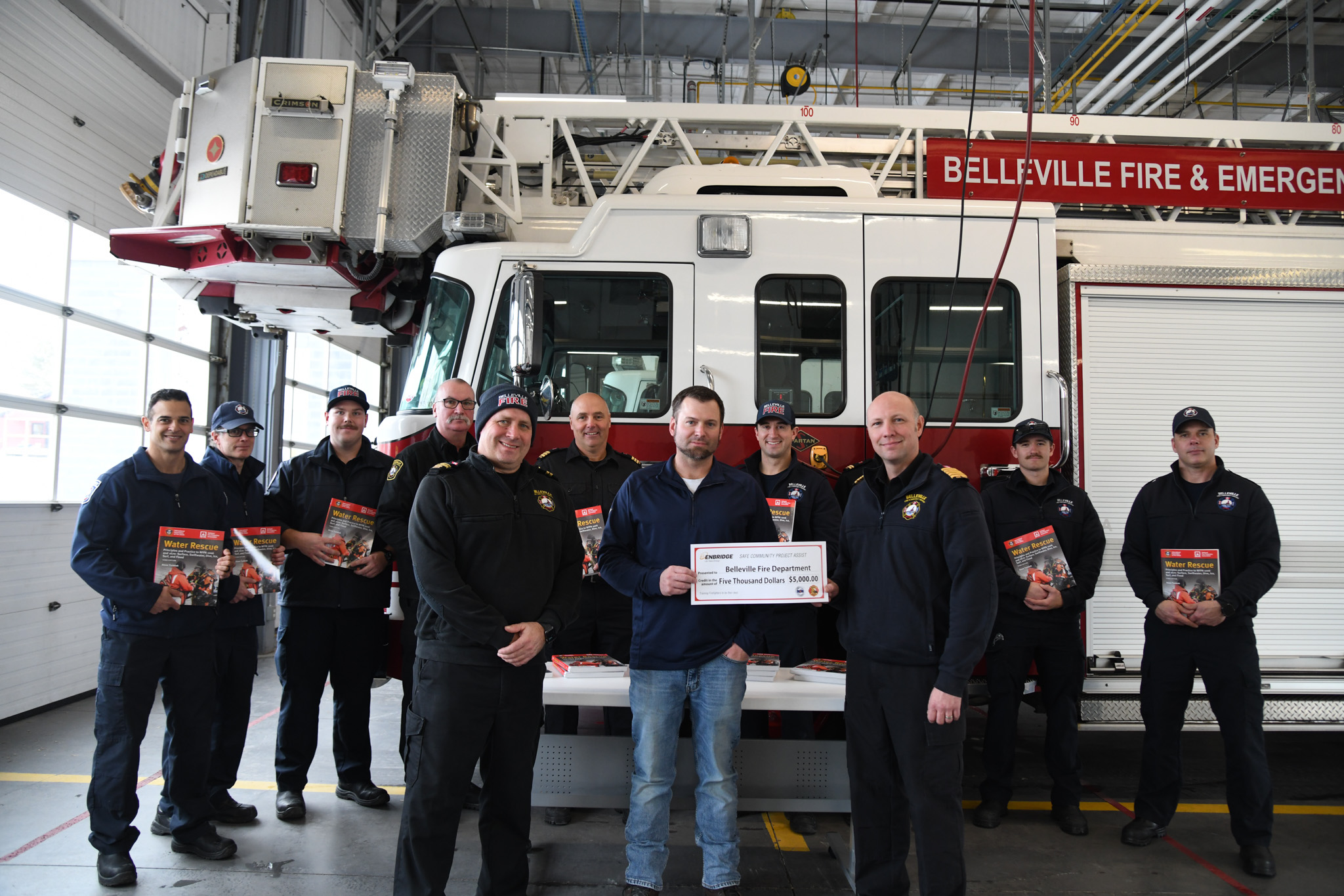 Belleville fire and Enbridge representatives hold new text books at fire hall