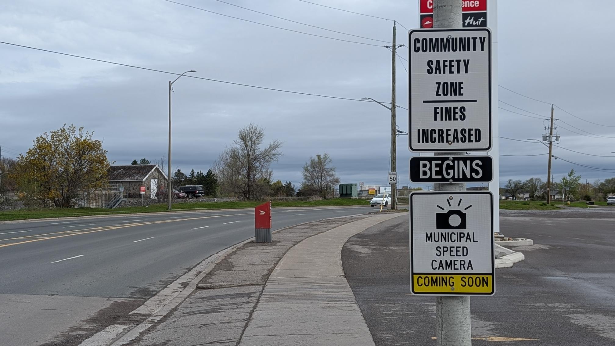 street sign that reads, "Community Safety zone, fines increased" with sign below reading, "Municipal speed camera coming soon"