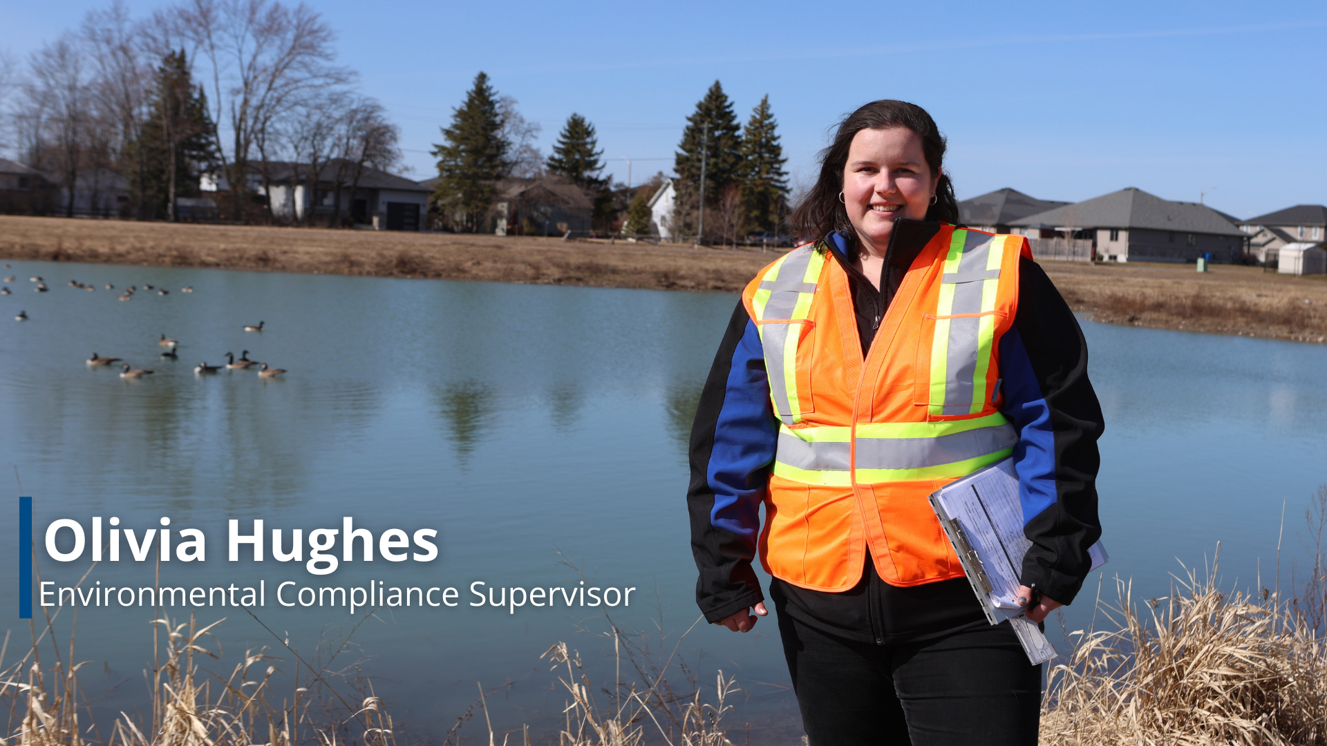 A photo of Olivia Hughes, a Environmental Compliance Supervisor in front of a storm water pond.