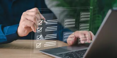 Person checking off list while working on computer