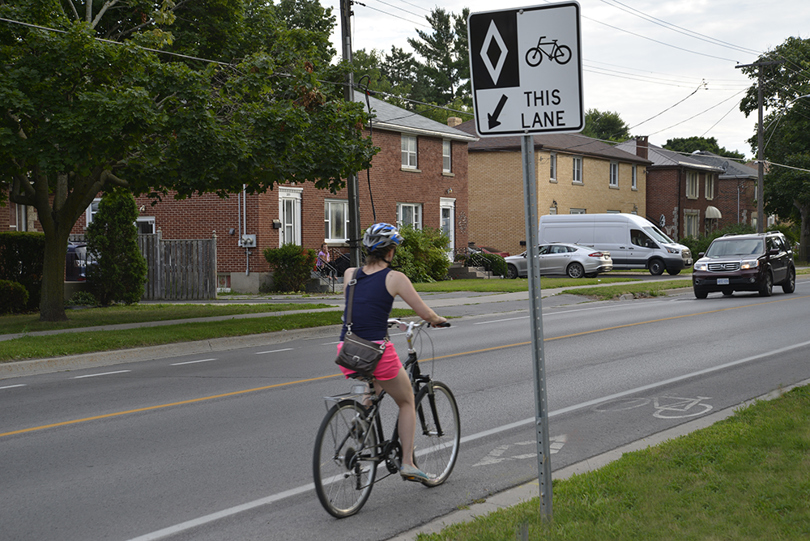 Photo of a cyclist riding in a bike lane along a road.
