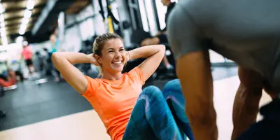 Woman doing sit up with trainer