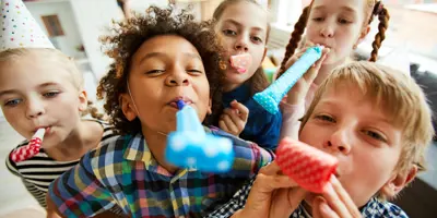 Kids wearing party hats using noise makers