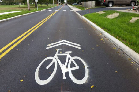 Image of a road with a marking on the road of a bicycle with arrows above it to indicate that the road is shared with cyclists.