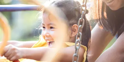 Mother pushes daughter on swing
