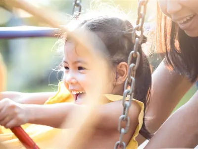 Mother pushes daughter on swing