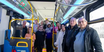 Council and transit staff with student artists on bus