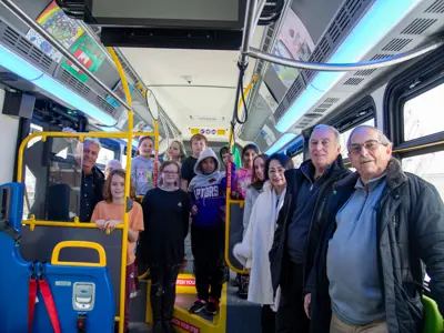 Council and transit staff with student artists on bus